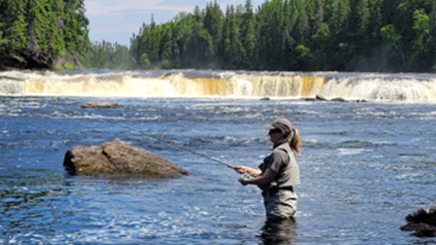 Woman fishing near waterfall